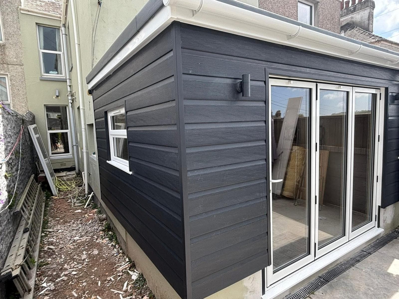 Completed garden room with dark horizontal cladding and glazed doors
